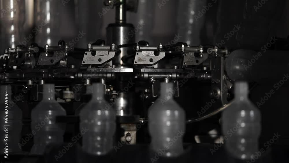 Poster close up shot of plastic bottles on a rotating machine at a factory being prepared to be filled with