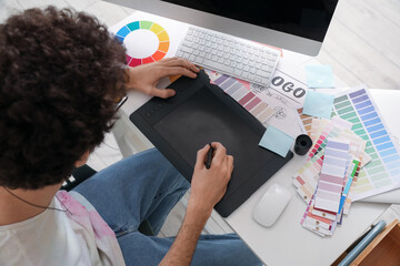 Male graphic designer working with tablet at table in office, closeup