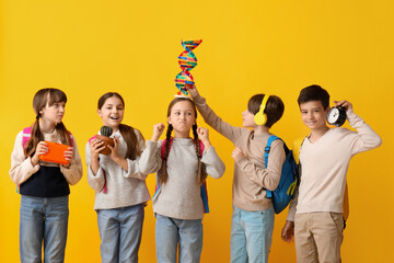 Little pupils with backpacks on yellow background