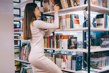 Optimistic lady picking book in library