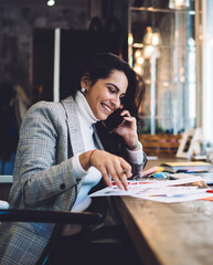 Fototapeta premium Cheerful remote worker calling on mobile creating project