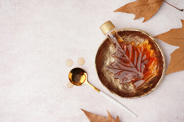 Bottle of tasty maple syrup on light background