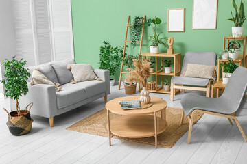 Interior of modern living room with grey sofa, armchairs, coffee table and houseplants