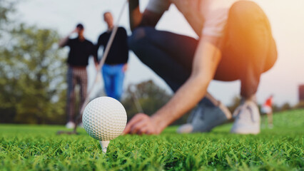 A man is placing a golf ball on a tee on a golf course.