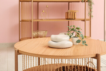 Wooden coffee table with houseplant and decor in interior of living room