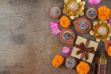 Diwali holiday concept with sweet traditional dessert, gift box and decorations on dark background....