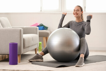 Happy young woman with fitball at home