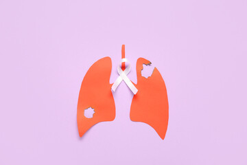 Paper lungs with burnt holes and white ribbon on lilac background. Lung cancer concept