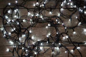 Fototapeta na wymiar Christmas lights on dark wooden background