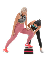 Obraz premium Mature woman training with stepper and rehabilitation therapist on white background