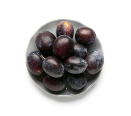 Plate with ripe plums on white background