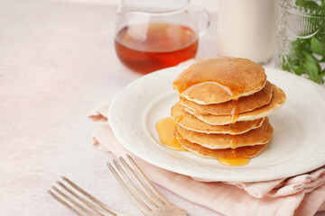 Plate of tasty pancakes with maple syrup on white background