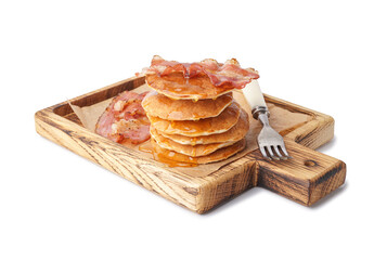 Wooden board of tasty pancakes with bacon and maple syrup on white background