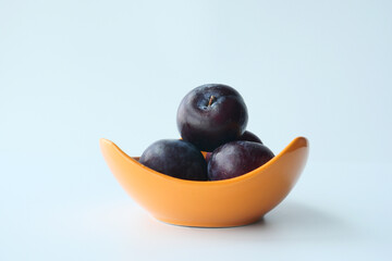 Fresh plums in a bowl on table 
