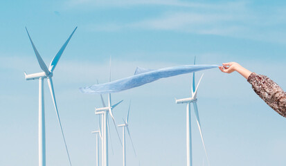 woman's hands enjoying the breeze In the wind energy farm and a wind turbine in behind