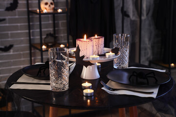 Festive table setting with burning candles and spiders for Halloween party