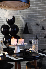 Festive table setting with burning candles and spiders for Halloween party
