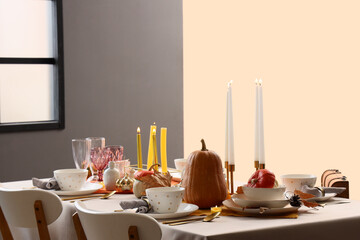 Festive table setting with burning candles and pumpkins for Halloween party at home