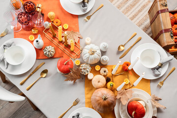 Autumn table setting with pumpkins, burning candles and dry leaves for Halloween party