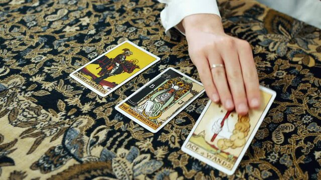 A woman giving a tarot reading with the knight of pentacles the high priestess and the ace of wands cards.