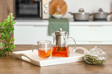 Tray with teapot and glass cup on table in kitchen