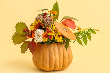 Beautiful autumn bouquet with leaves in pumpkin on yellow background