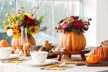 Festive table setting with bouquets of autumn flowers in pumpkins