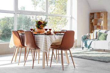 Pumpkin with autumn bouquet on festive dining table in room