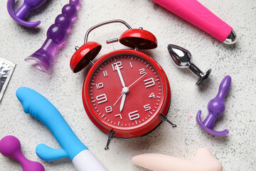Alarm clock with different toys on grunge white background. Time for sex