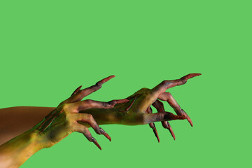 Fototapeta premium Hands of witch with claws on green background. Halloween celebration