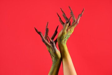 Obraz premium Hands of witch with claws on red background. Halloween celebration