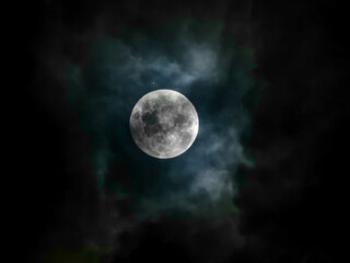 Full Moon in behind clouds on the night sky. Halloween night. All Hallows Eves. Horror sky