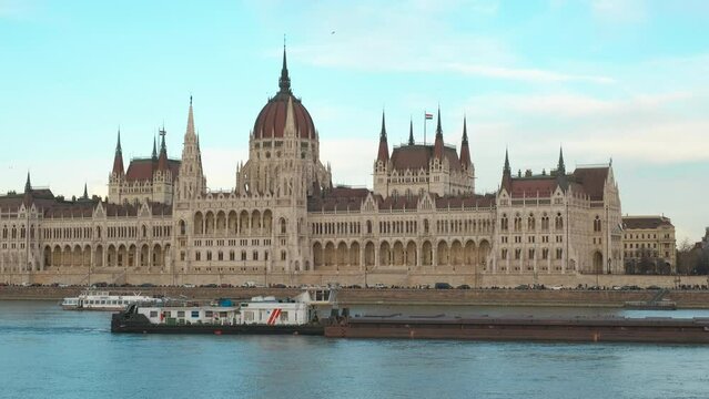 Tourists sailing by budapest parliament. A view of sailing trip on the Danube river against sunny Budapest building facade in the day light.