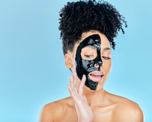 Skincare, charcoal mask and woman in studio for facial treatment, anti aging detox and wellness. Beauty, salon and face of person with product for health, cosmetics or grooming on blue background