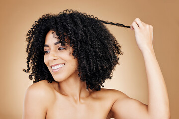 Curly, hair and strand of woman in studio for natural beauty, healthy growth and coil textures on brown background. Model, smile and pull afro hairstyle for salon aesthetic, keratin treatment or care