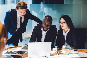 Business people watching laptop working in collaboration in boardroom
