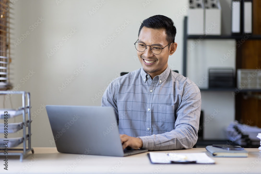 Wall mural portrait of stylish asian businessman works on laptop, does data analysis and creative designer, loo