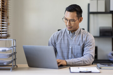 Portrait of Stylish Asian Businessman Works on Laptop, Does Data Analysis and Creative Designer, Looks at Camera and Smiles. Digital Entrepreneur Works on e-Commerce Startup Project