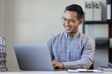 Portrait of Stylish Asian Businessman Works on Laptop, Does Data Analysis and Creative Designer, Looks at Camera and Smiles. Digital Entrepreneur Works on e-Commerce Startup Project