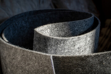 Dense thin gray felt close-up. Thick non-woven textile material made from felted wool in a roll