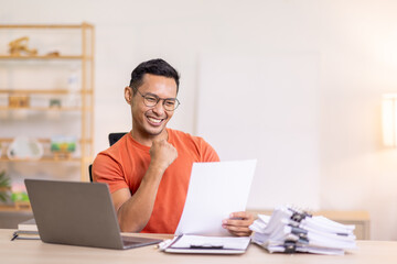 Excited Asian man sit at desk feel euphoric win online lottery, happy asian man overjoyed get mail...
