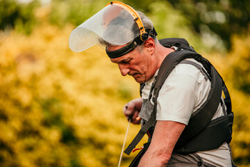 Naklejka premium A seasoned gardener, this senior man gears up to trim the grass in his backyard