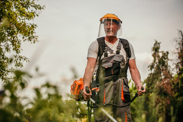 Experienced senior gardener taking care of his yard with precision, wearing a protective work suit...