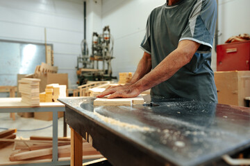 Close up of male carpenter working with piece of wood in a workshop