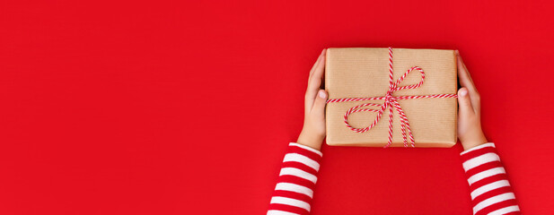 gift box in children's hands on a red background, presenting a gift with place for text