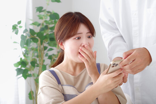 男性のスマホを見て複雑な表情をする女性
