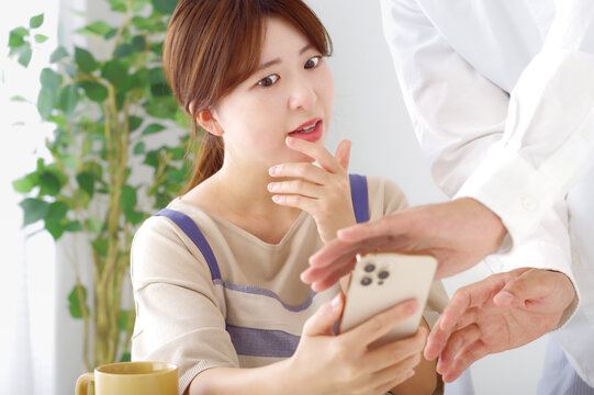 男性のスマホを見て複雑な表情をする女性