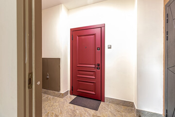 The close up image of a newly installed front door on a home. The door is a deep red, berry color