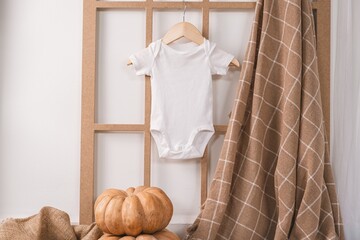 Fototapeta na wymiar White newborn baby short sleeve bodysuit with autumn decor, plaid and pumpkins ideal boho kid apparel autumn mockup for presentation child designs on October holidays Halloween and Thanksgiving 