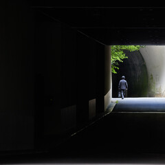 暗いトンネルを通過している歩く男性の後姿